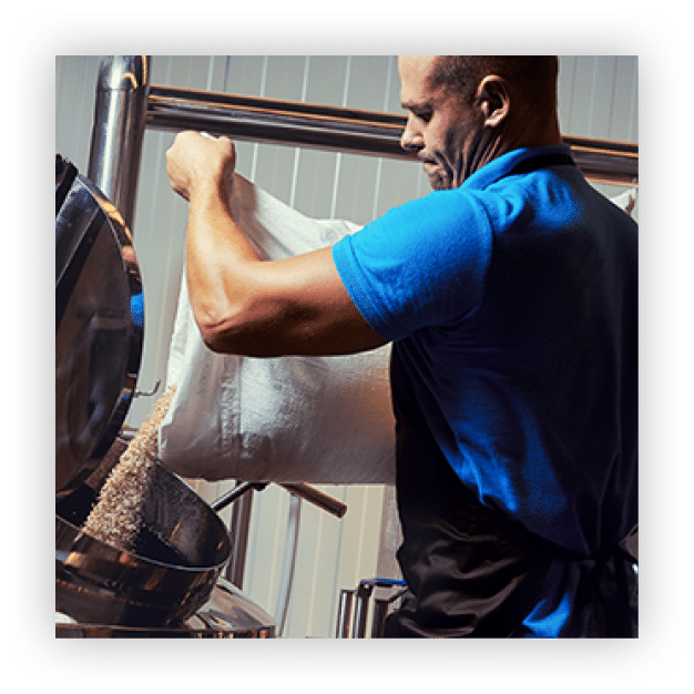 Brewer in brewhouse pouring out the malt to the tank